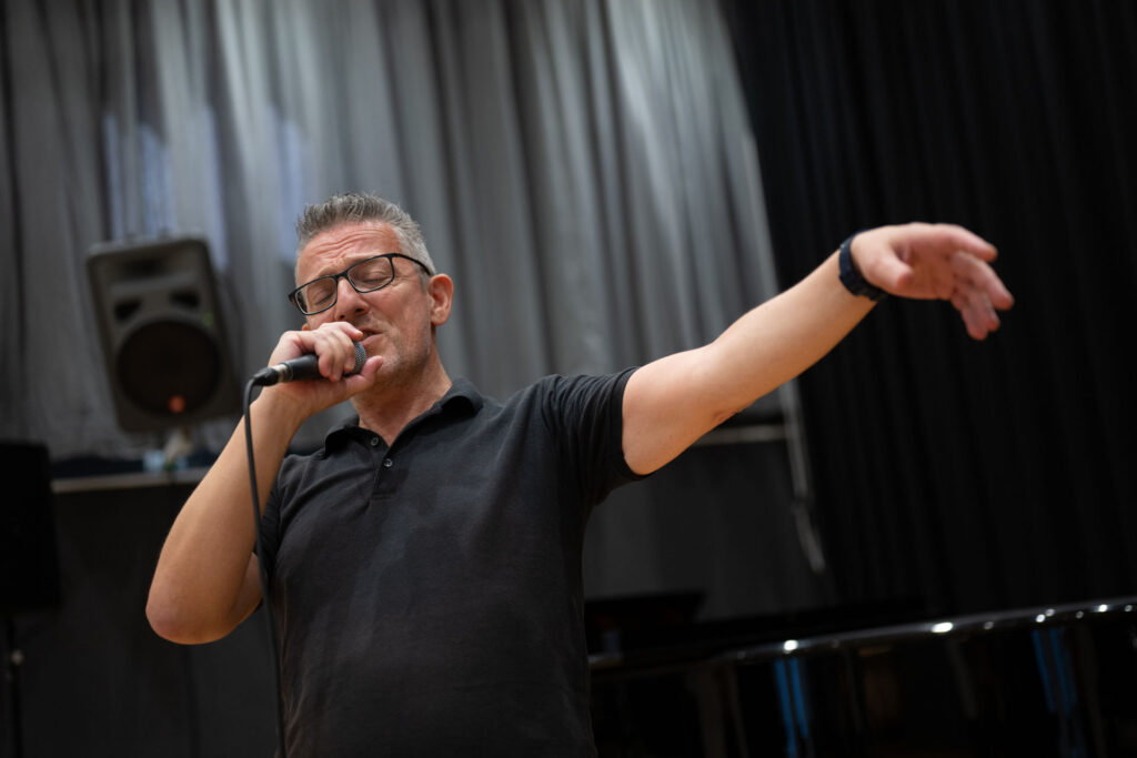 Bernd Koholzer am Mikrofon, mit ausgestrecktem Arm